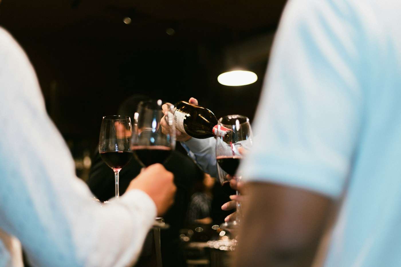 Varias personas brindan con copas de vino tinto en la mesa